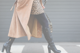 Woman wearing cheetah print dress, brown trench coat, and leather boots