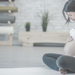 Pregnant woman sitting criss-cross on floor while massaging stomach