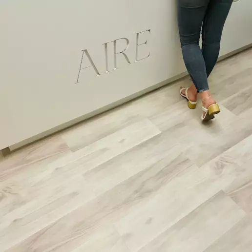 Carving of AIRE on wall next to woman in wedges